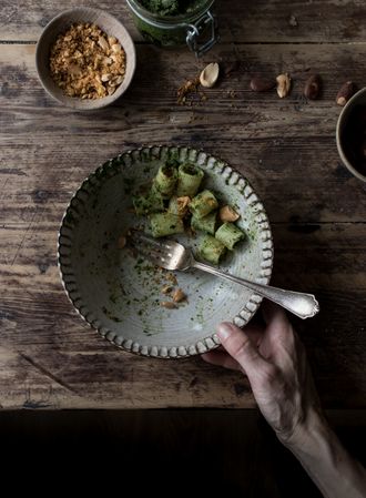 Hands taking pasta paccheri with kale pesto and nuts