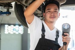 Male auto repairman working on undercarriage of vehicle