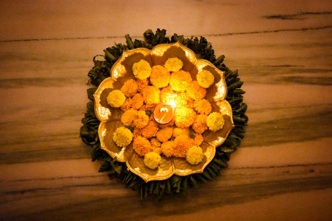 Top view of marigold flowers surrounded by Diya on tray
