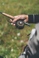 Man carrying fishing rod and standing at meadow