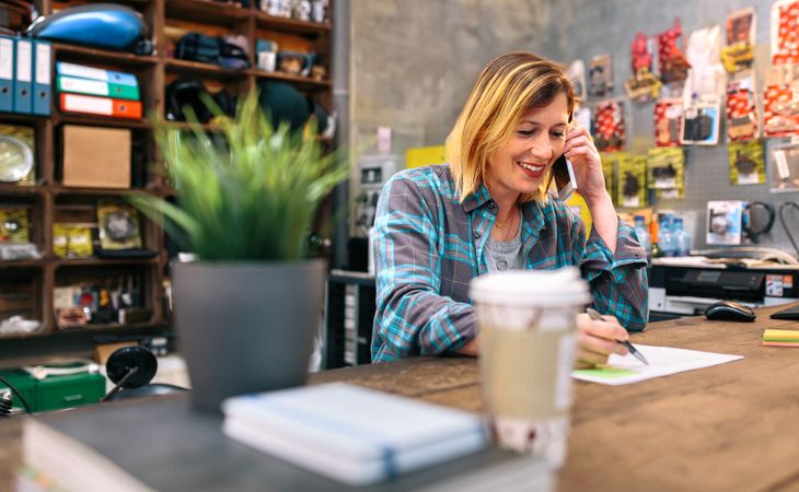 Smiling blonde young woman talking by cellphone in a store.