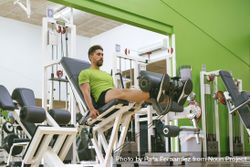 Male in green t-shirt working out quads using gym equipment 48z8v0