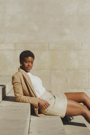 Stylish Black woman sitting on steps on street