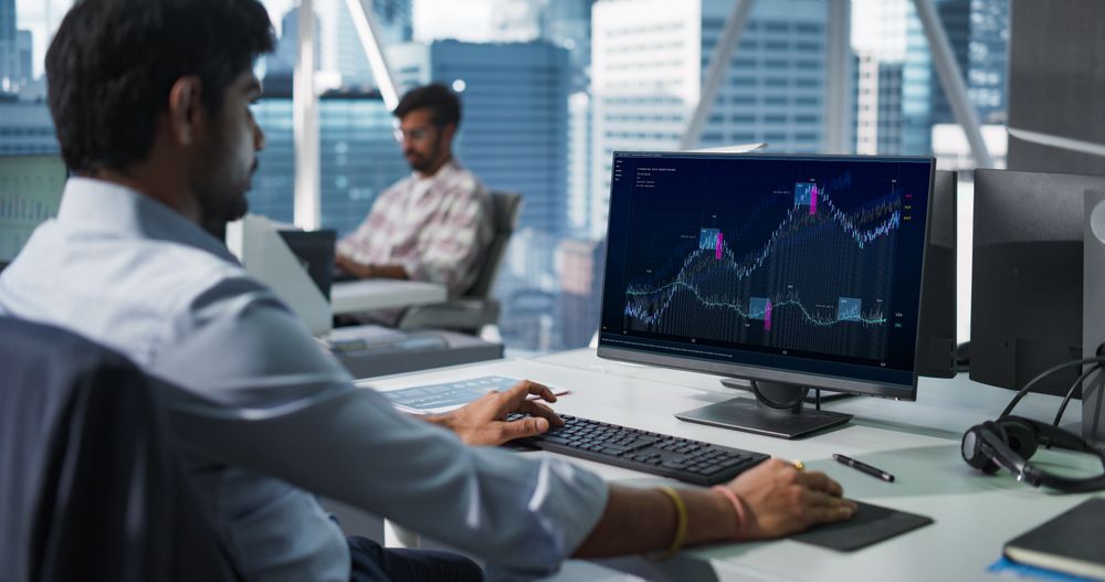 Hedge Fund Office: Indian Financial Analyst Using Computer with Display Showing Real-Time Stocks