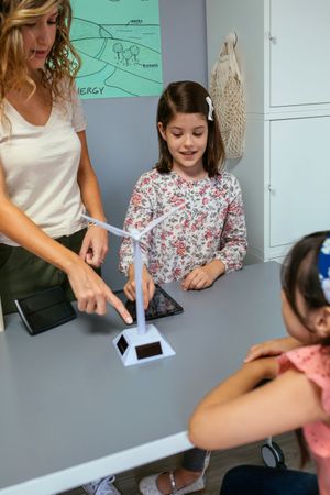 Student showing solar windmill to classmate in ecology classroom