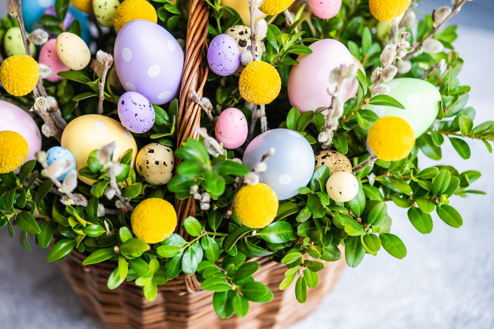 Close up of pastel Easter eggs & flowers in decorative basket