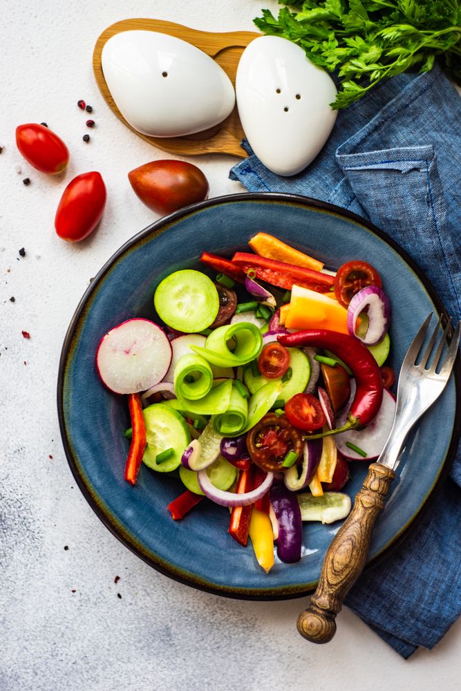 Top view of healthy raw vegetable salad served on blue plate