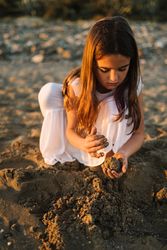 Adorable girl playing with sand on beach