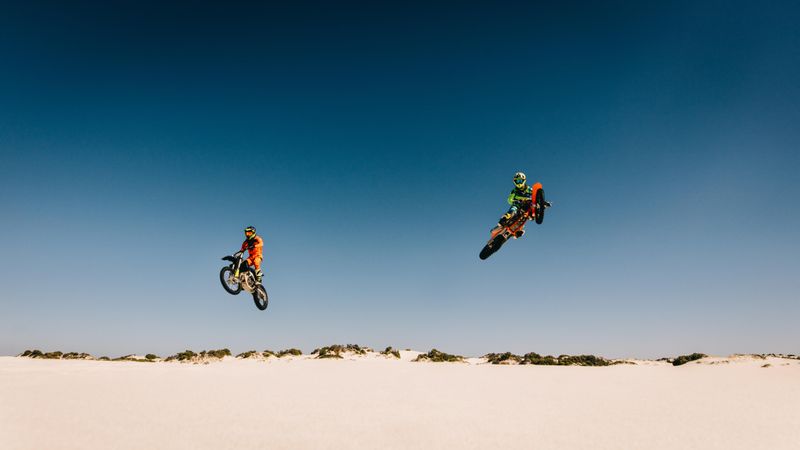 Motocross racers jumping bikes and doing stunts in desert