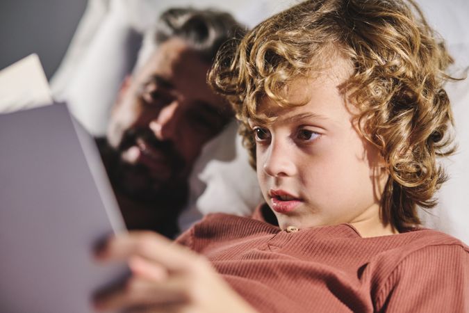 Man and boy reading together in bedroom