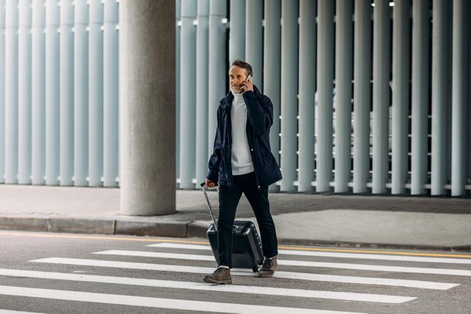 Man on crosswalk using phone leaving airport