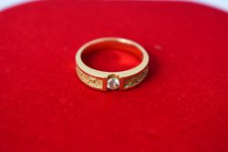 Man's diamond gold ring on red fabric with copy space