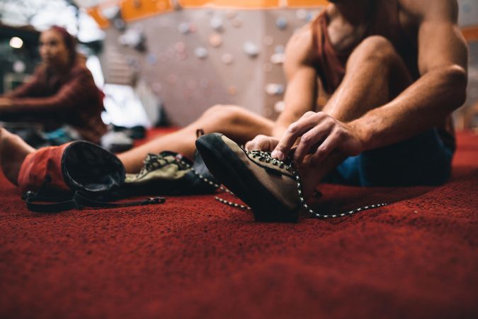 Cropped shot of man tying shoe laces at wall climbing gym