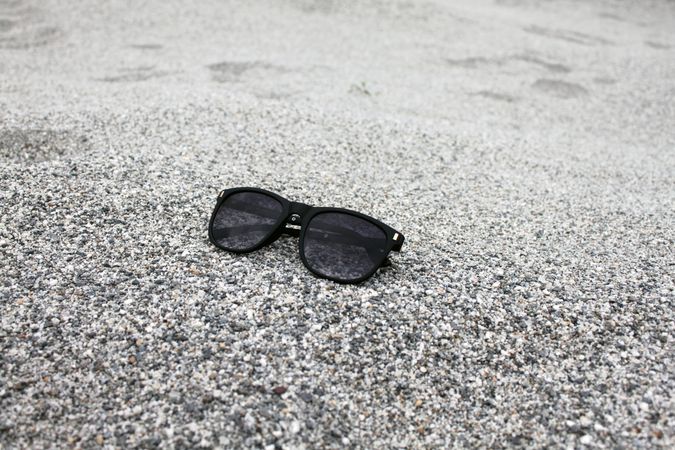 Sunglasses sitting on grey sandy beach