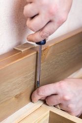Cropped image of carpenter driving a nail into piece if wood bDMQK0