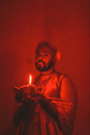 Portrait of Indian man holding a diya in red lit studio