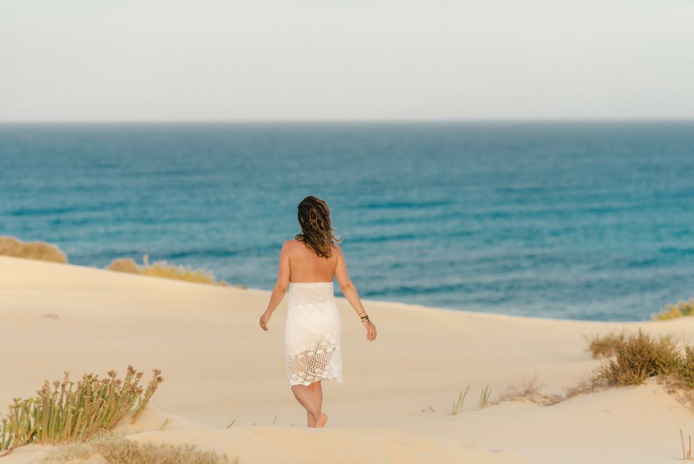 Active woman in white shorts walking sandy beach