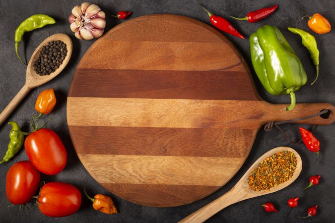 Empty pizza  board on the table with Ingredients for cooking. Tomatoes, various peppers, garlic and green peppers.