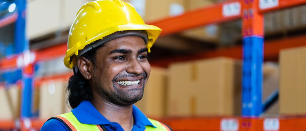 Smiling employee in the warehouse, wide