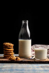 Milk and fresh cookies on board near napkin