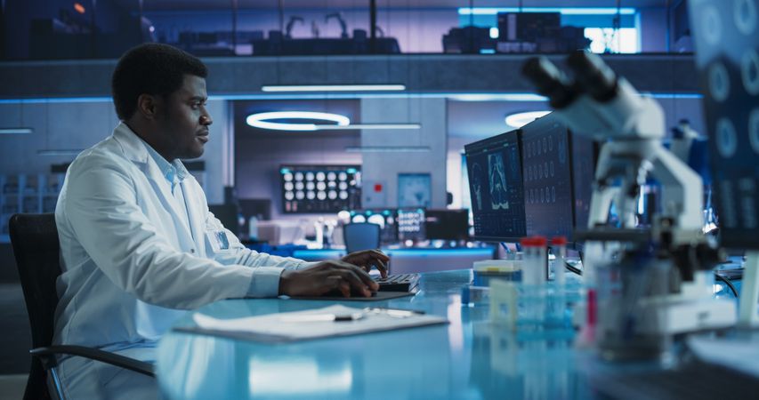 Black Male Neuroscientist Using Desktop Computer To Analyze MRI Scans Of Brain In Medical Research Center Laboratory.