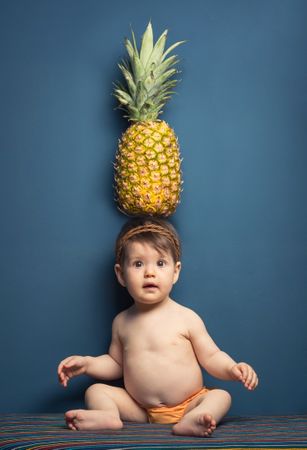 Happy baby holding a pineapple over her head