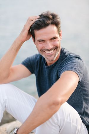 Cheerful man touching head on shore