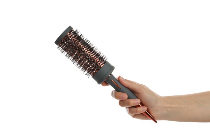 Female hand holds hair brush, isolated on blank background