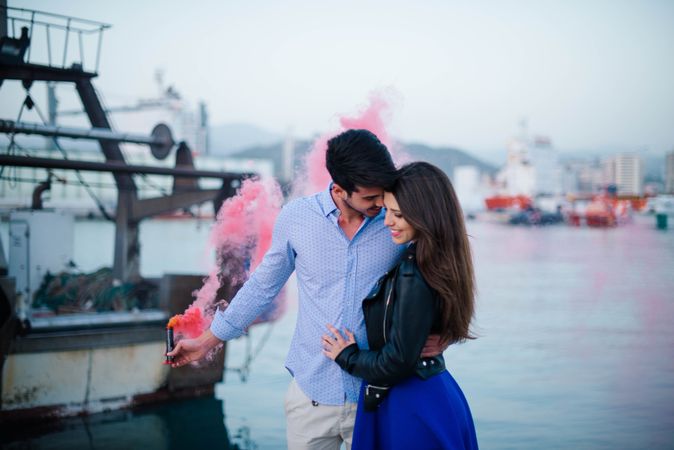 Young man holding smoke bomb and hugging woman being in love
