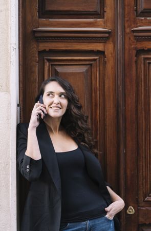 Young female using mobile phone on wooden door