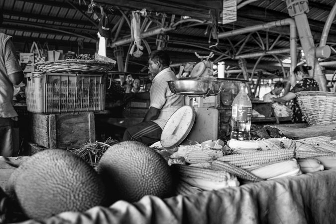 Man sits at vegetable and fruit stall at market