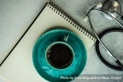 Coffee in teal cup with phone, stethoscope and notepad 5aX7BQ