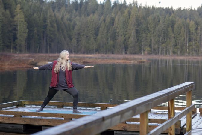 Woman doing yoga on a lake dock
