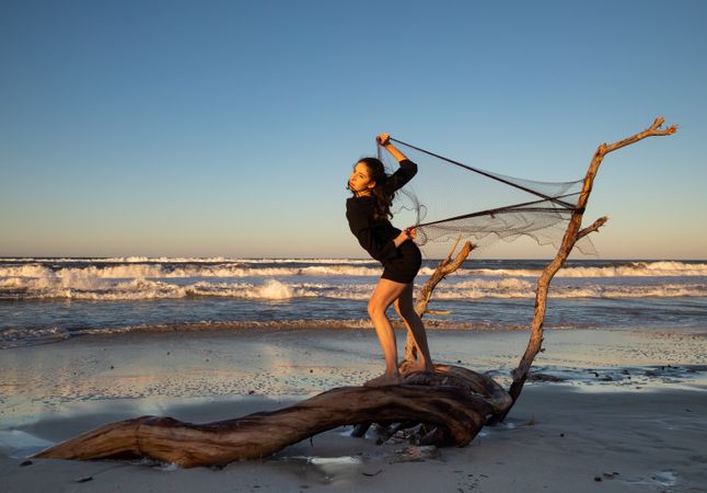 Woman in fishing net fixed on twig near water on shore
