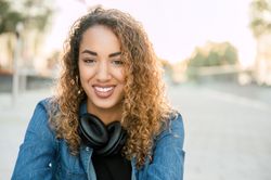 Smiling woman with wireless headphones on street