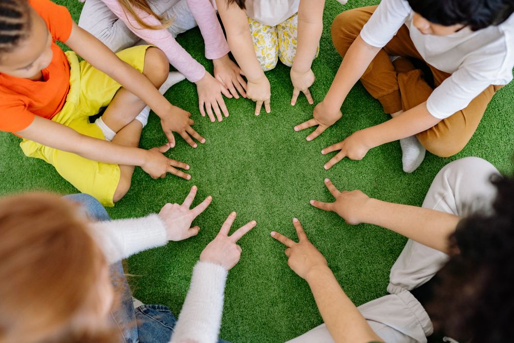 Top view of group of children sitting on the grass in circle