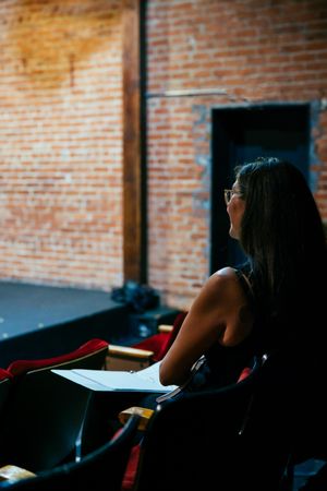 Female director looking onto stage with script in front of her
