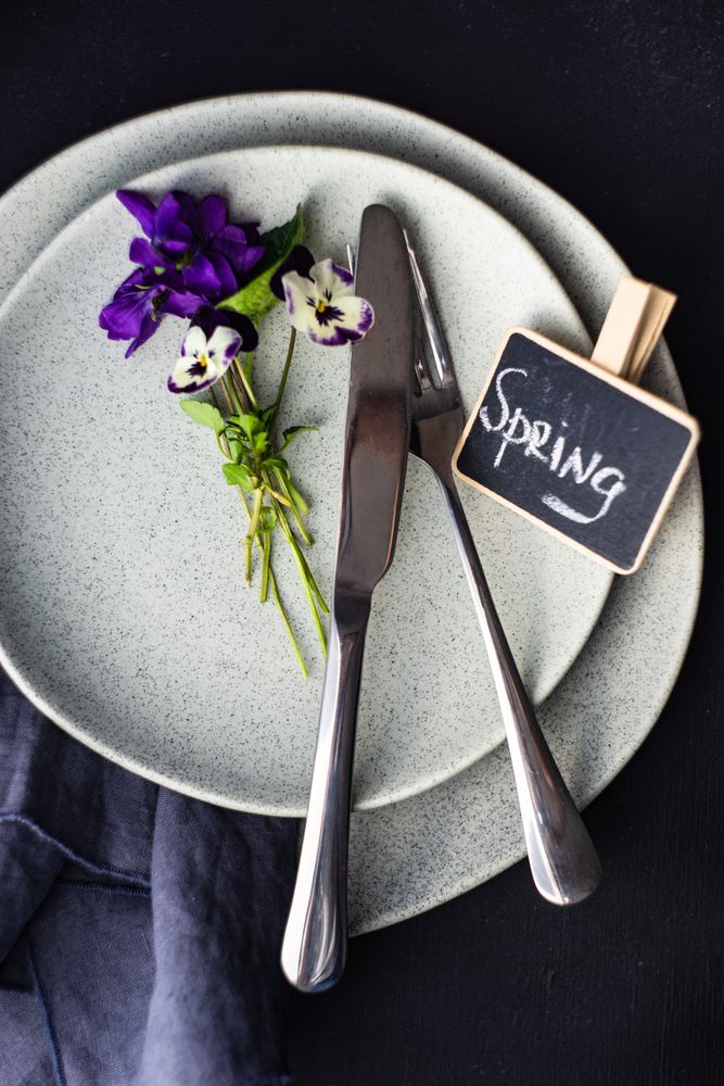 Top view of spring table setting for dinner with delicate purple flowers