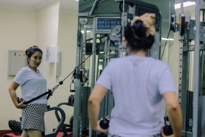 A woman uses a cable exercise machine at a gym