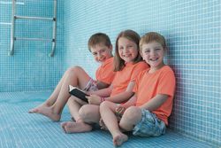 Children sitting in empty pool and reading book