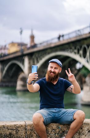 Satisfied male tourist taking selfie on smartphone at quay