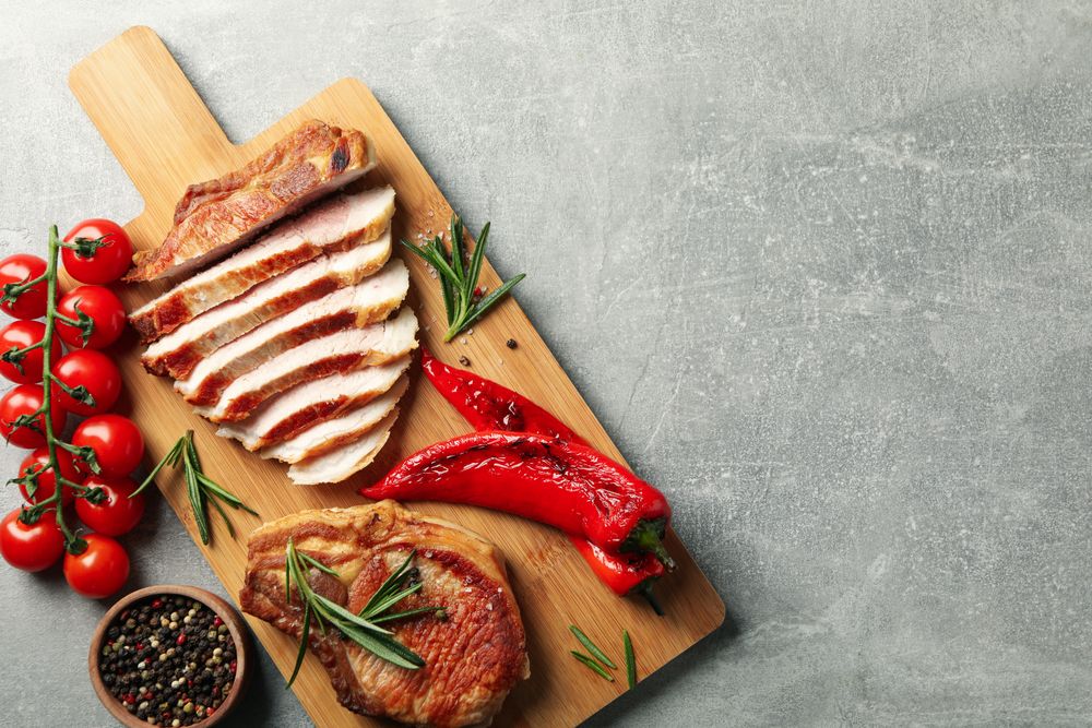 Board with fried steaks on gray background. Grilled food