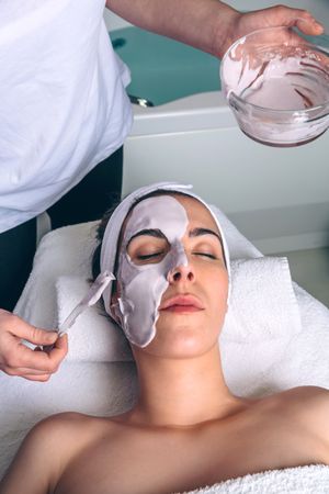 Woman resting with eyes closed while having a clay mask applied