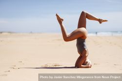 Woman doing headstand on the sand at a Spanish beach 0WpmM5