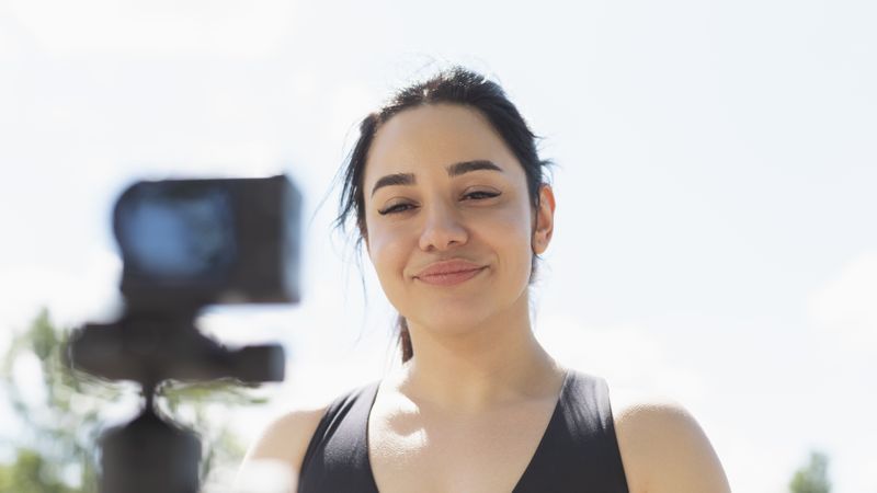 Closeup of a young woman that records herself on video, to explain to her followers, how to perform an exercise and sport workout