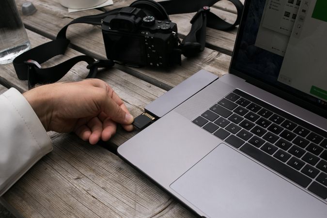 Photographer inserting memory card into laptop