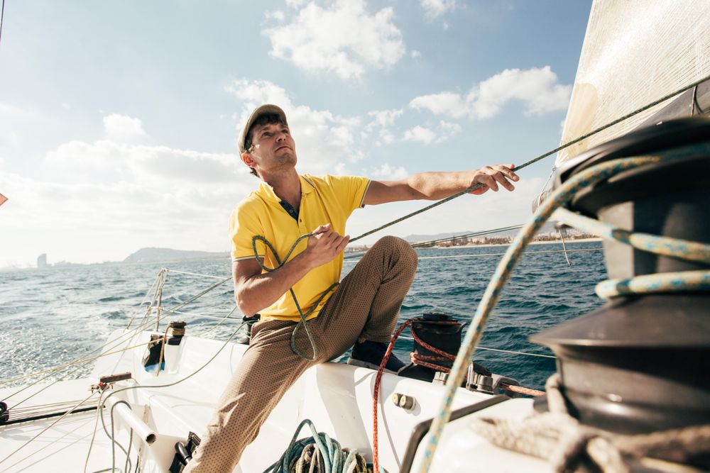 Man on yacht pulling the sail