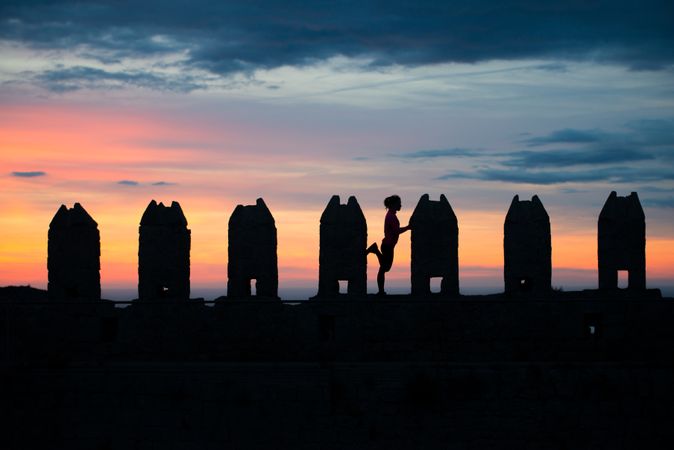 Silhouette of person between stone sculptures in sunset