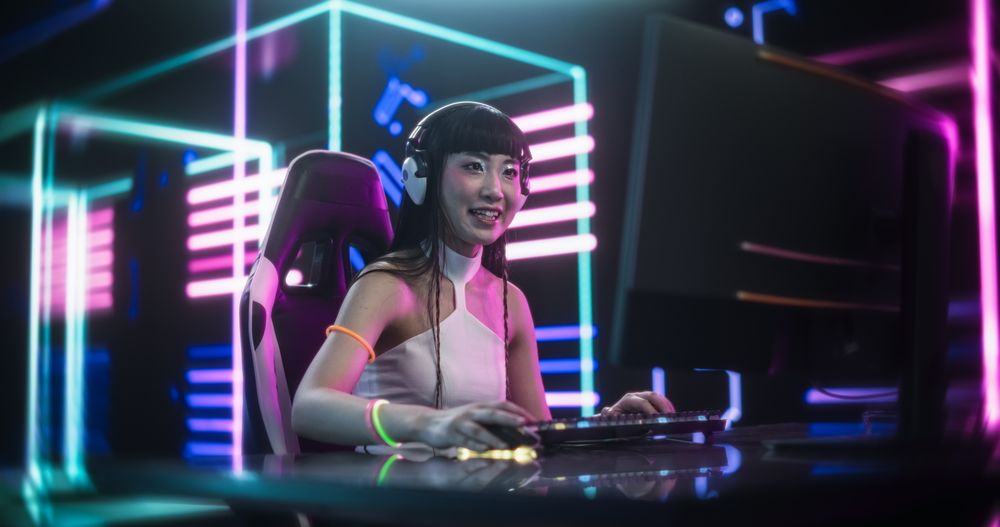 Focused Japanese Young Woman Playing Video Games on a Computer in a Technologically Advanced Room with Futuristic Neon Background.