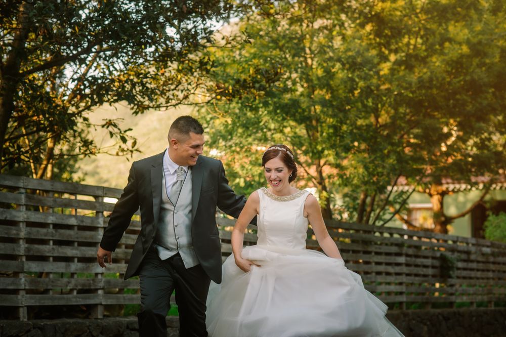 Happy just married couple running along fence in garden